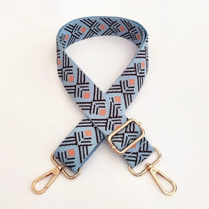Detail of adjustable blue canvas strap with ethnic geometric embroidery and gold hardware