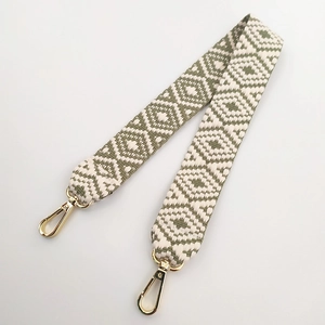 Detail of green and white geometric woven wide handbag strap with gold metal lobster clasps