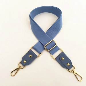 Close-up of blue woven strap with gold metal buckle and leather reinforced ends