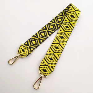 Close-up of ethnic geometric woven purse strap with yellow and blue patterns and gold clips