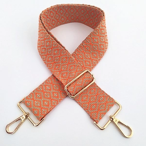 Détail de la bandoulière tissée réglable avec motifs géométriques oranges et boucles dorées