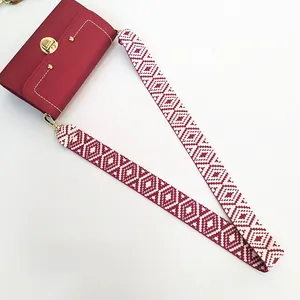 Ethnic style woven wide shoulder strap on a red square crossbody bag with gold buckle