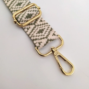 Détail de la sangle de sac en jacquard vert sauge avec boucles dorées et mousqueton