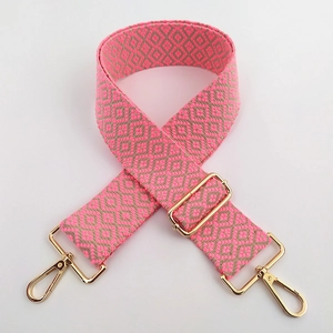 Détail d'une bandoulière ajustable en coton avec motif rose et mousquetons dorés
