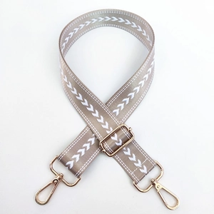 Detail von Taschenriemen aus khakifarbenem Nylon mit weißem V-Muster und Goldkarabinern