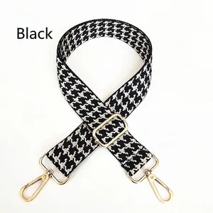 Close-up of black and white houndstooth bag strap with adjustable gold lobster clasps