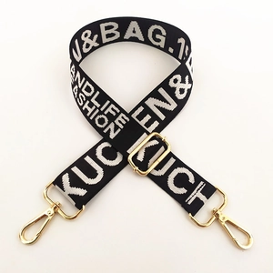 Detail of black and white woven bag strap with golden metal hooks and adjustable buckle