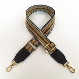 Close-up of adjustable striped canvas strap with gold metal buckles and leather ends