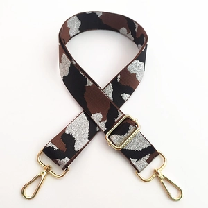 Detail of adjustable camouflage bag strap with metallic threads and golden lobster clasps
