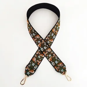 Close-up of wide floral embroidery shoulder strap with gold swivel lobster clasps