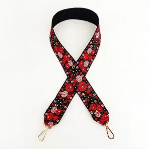 Close-up of ethnic embroidered flower bag strap with gold lobster clasps on white background
