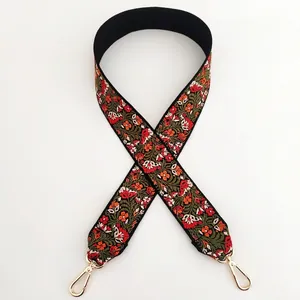 Detail of ethnic embroidery strap with red floral patterns and gold lobster clasps