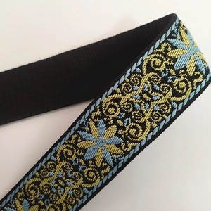 Close-up of ethnic embroidered bag strap with blue flowers and yellow floral jacquard pattern