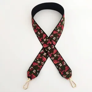 Detail of embroidered floral bag strap with pink flowers and gold metal hooks