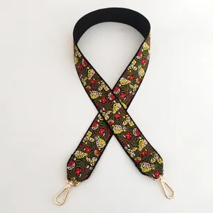 Close-up of ethnic style embroidered shoulder strap with floral patterns and gold metal hooks