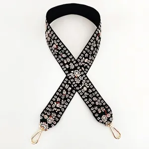 Close-up of wide embroidered shoulder strap with floral patterns and golden swivel hooks