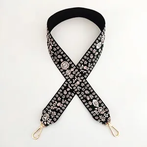 Detail of embroidered floral bag strap in black with light gold metal swivel hooks
