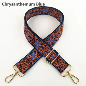 Close-up of ethnic style embroidered bag strap with floral pattern and gold metal hooks