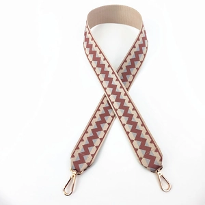 Close-up of geometric jacquard bag strap with gold lobster clasps and brown zigzag patterns