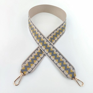 Close-up of geometric zigzag patterned beige fabric strap with gold lobster clasps