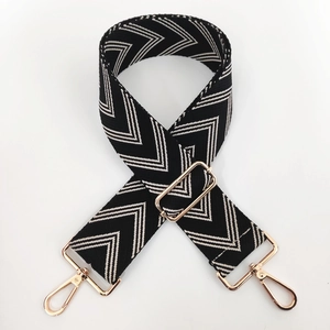 Detail of black and white V-patterned wide shoulder strap with rose gold metal clasps