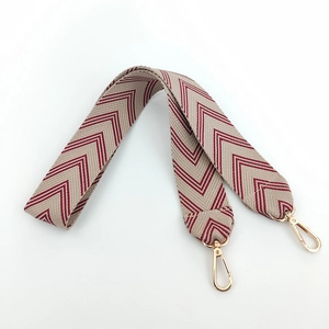 Detail of wide jacquard embroidered bag strap with brown herringbone pattern and gold hooks