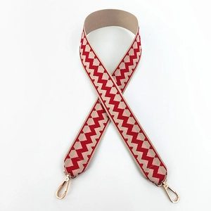 Detail of red chevron woven cotton bag strap with polished gold-tone lobster clasps