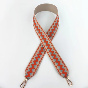 Detail of wide woven strap with orange and blue zigzag pattern and gold metal clips