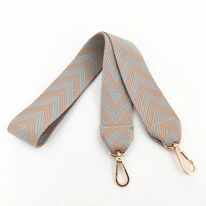 Close-up of chevron canvas bag strap with beige and light blue embroidery and gold hooks