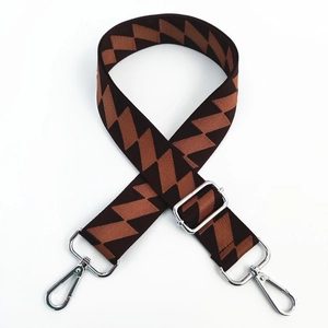 Detail of adjustable woven shoulder strap with brown geometric pattern and silver lobster clasps