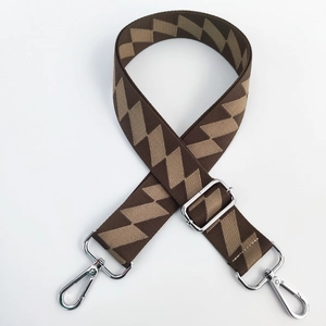Macro shot of brown and beige geometric woven shoulder strap with silver metal hooks