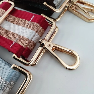 Close-up of durable nylon bag straps with shimmering gold metallic thread and golden clasps