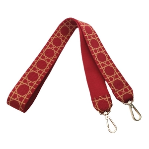Red embroidered handbag strap with golden geometric pattern and lobster clasps