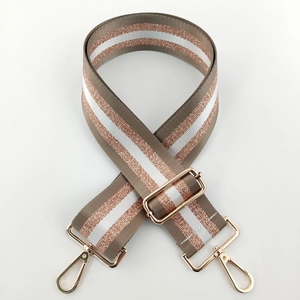 Detail of adjustable nylon bag strap with brown and rose gold glitter stripes and gold buckles