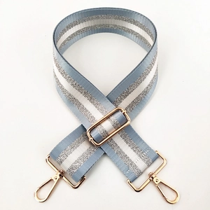 Detail of adjustable nylon bag strap with light blue white stripes and silver glitter accents