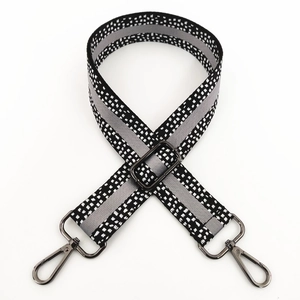 Close-up of adjustable wide woven bag strap with black white pixel pattern and metal clips