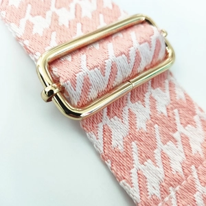 Detailed macro view of pink houndstooth woven strap with adjustable gold metal buckle