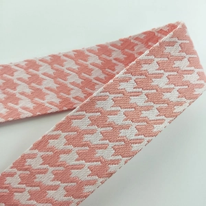 Detailed close-up of pink houndstooth jacquard woven bag strap with fine stitching