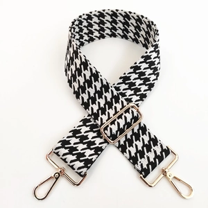 Close-up of thick houndstooth bag strap with light gold metal lobster clasps