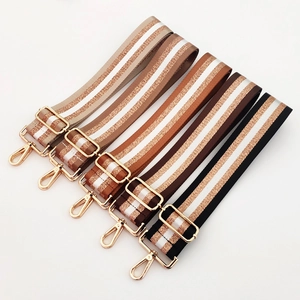 Detail of adjustable nylon bag straps with gold metallic stripes and golden hooks