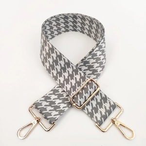 Detail of adjustable woven houndstooth bag strap with premium gold metal lobster clasps