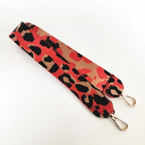 Détail d'une bandoulière en nylon à motif léopard avec des mousquetons en métal doré