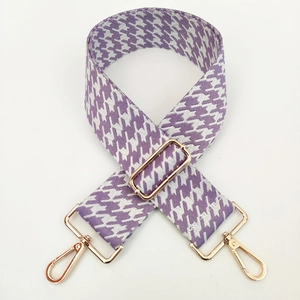 Close-up of jacquard houndstooth bag strap in purple and white with gold metal hooks