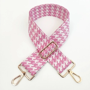 Detail of pink and white houndstooth woven strap with adjustable light gold metal buckles