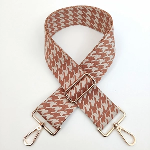 Detail of adjustable houndstooth shoulder strap with gold metal lobster clasps and buckle