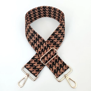 Close-up of thick jacquard woven houndstooth strap with golden metal lobster clasps