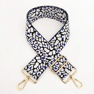 Detail of adjustable leopard print bag strap with gold metal hooks and blue pattern