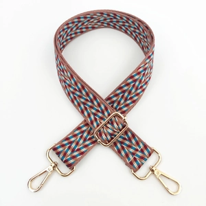 Detailed view of woven wide shoulder strap with geometric patterns and gold metal buckles