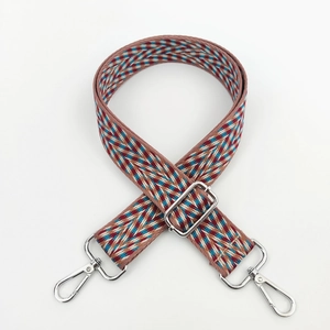 Close-up of colorful herringbone woven bag strap with silver metal buckle and lobster clasp