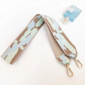 Close-up of woven bag strap with blue geometric patterns and golden metal lobster clasps